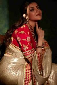 A beige saree and a red silk blouse with a silver necklace